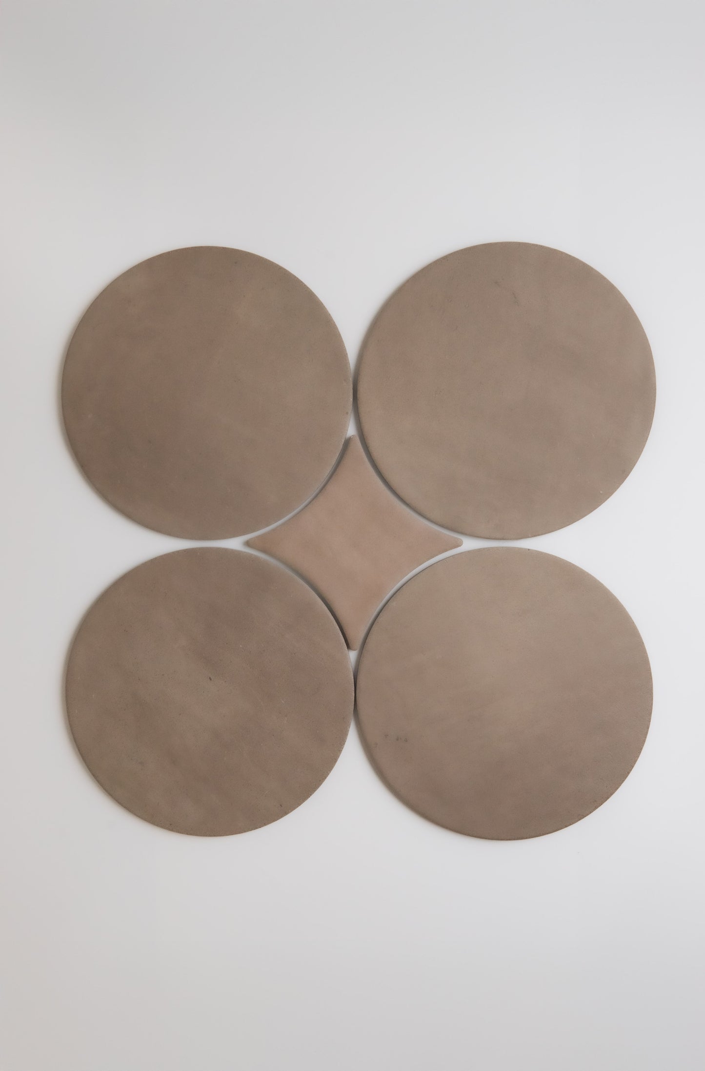Four large, brown Pampas discs by Finca arranged in a clover shape on a plain white background.