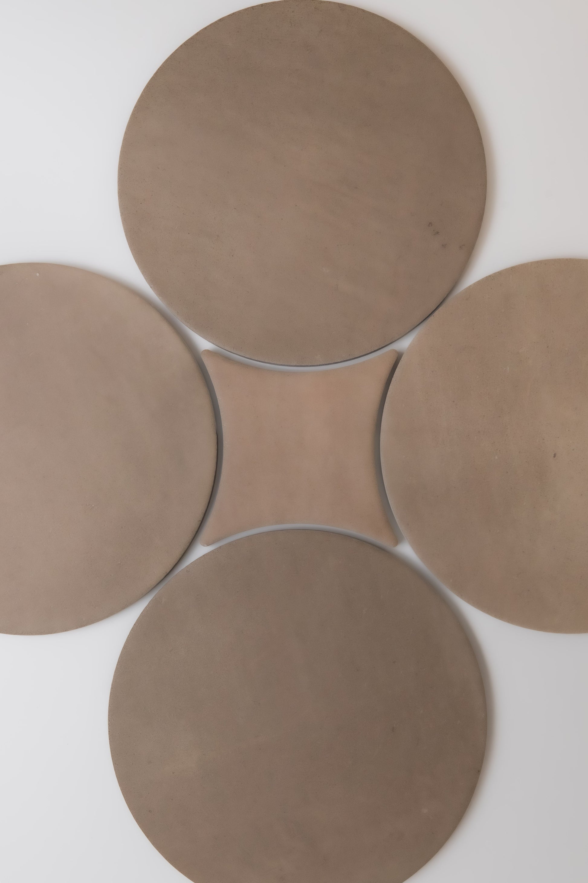 Four large round brown Pampas discs by Finca form a clover shape with a curved square center on a light background.