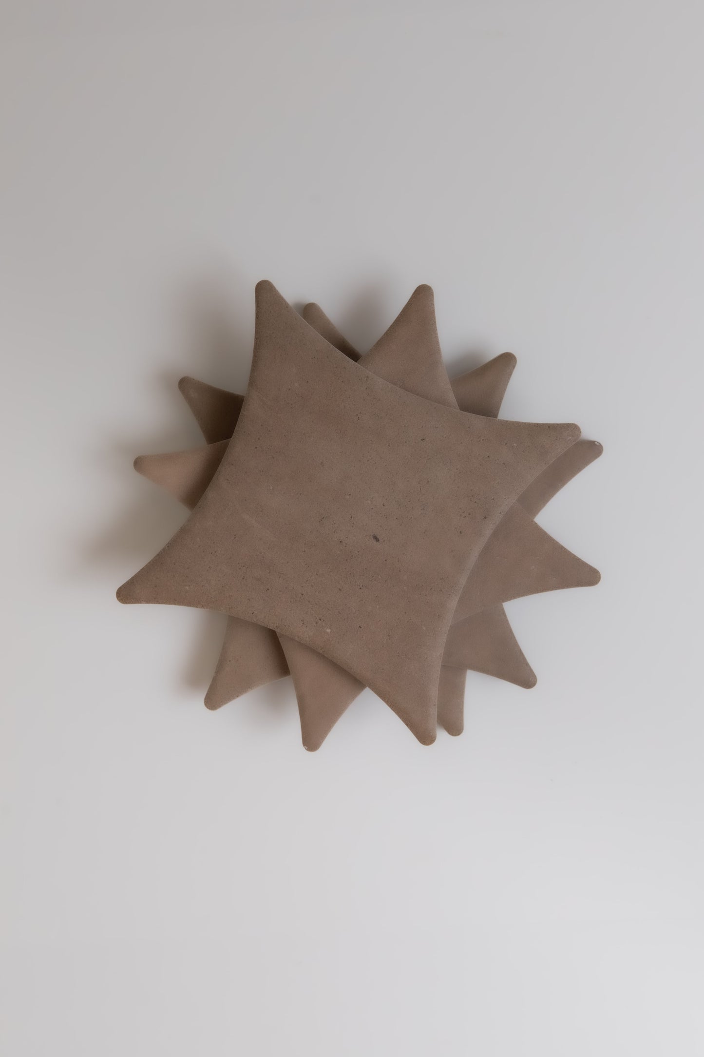Two layered, star-shaped beige Pampas ceramic pieces by Finca stacked on a white background, viewed from above.
