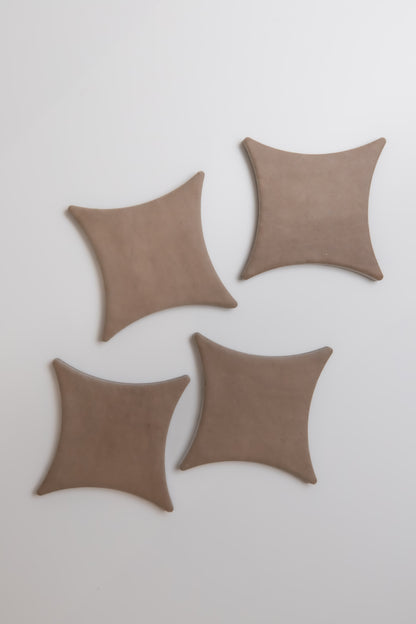 Four brown, square-shaped Pampas by Finca with concave sides, arranged on a white surface.