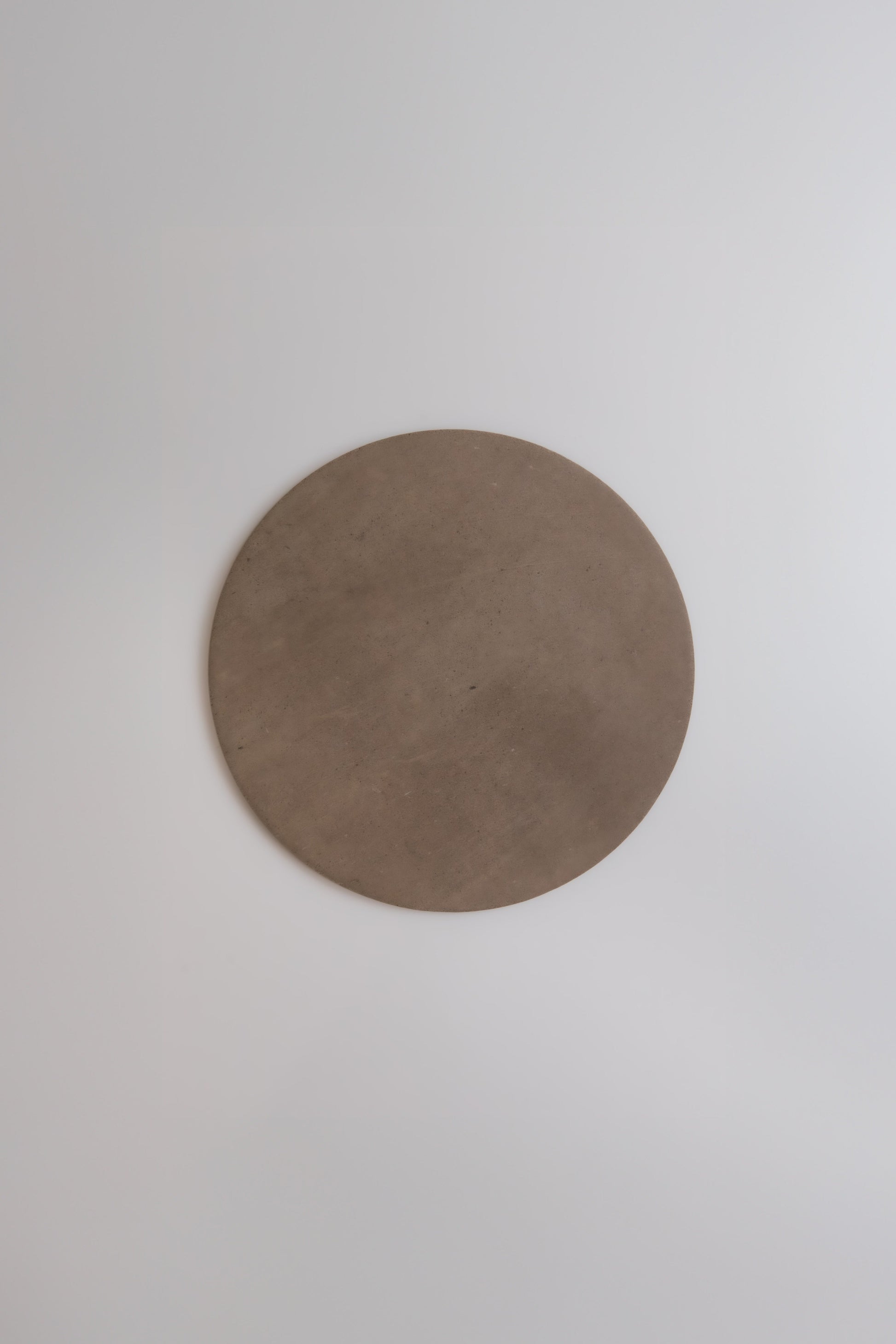 The Finca Pampas plate is a simple, round, brown ceramic displayed on a smooth white surface.