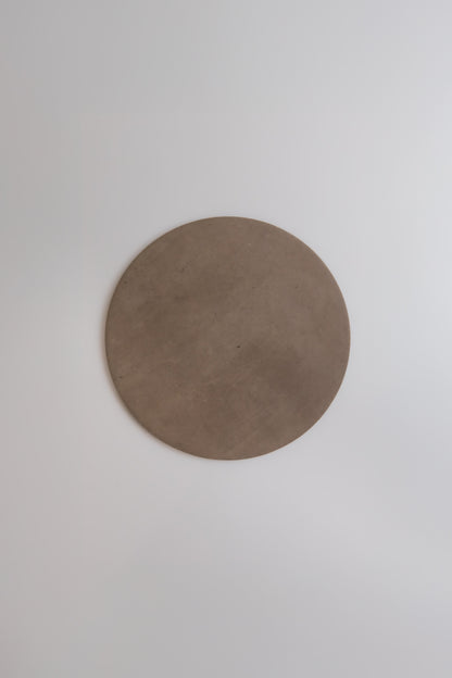 The Finca Pampas plate is a simple, round, brown ceramic displayed on a smooth white surface.