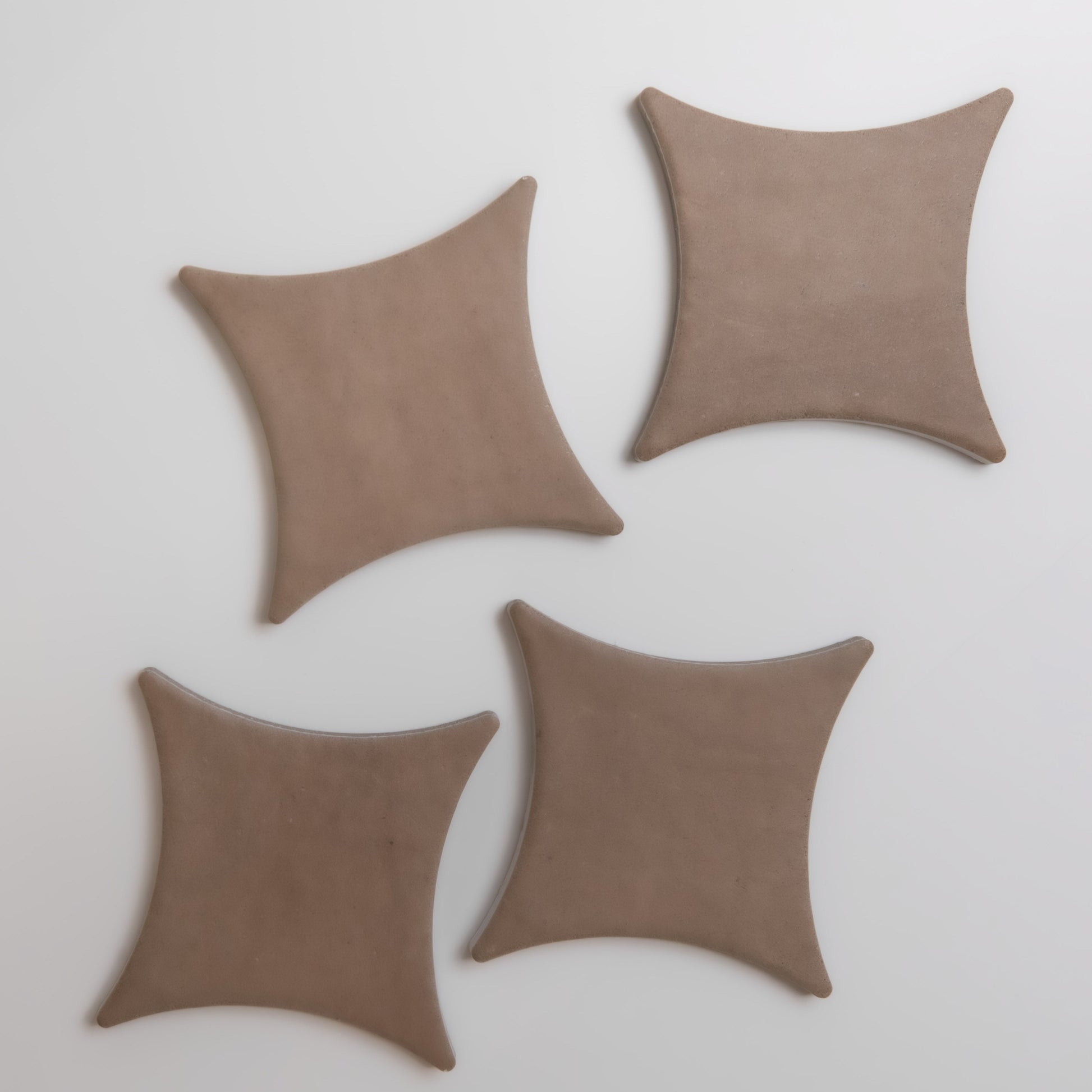 Four Finca Pampas, tan and square with concave sides, are arranged on a white surface.