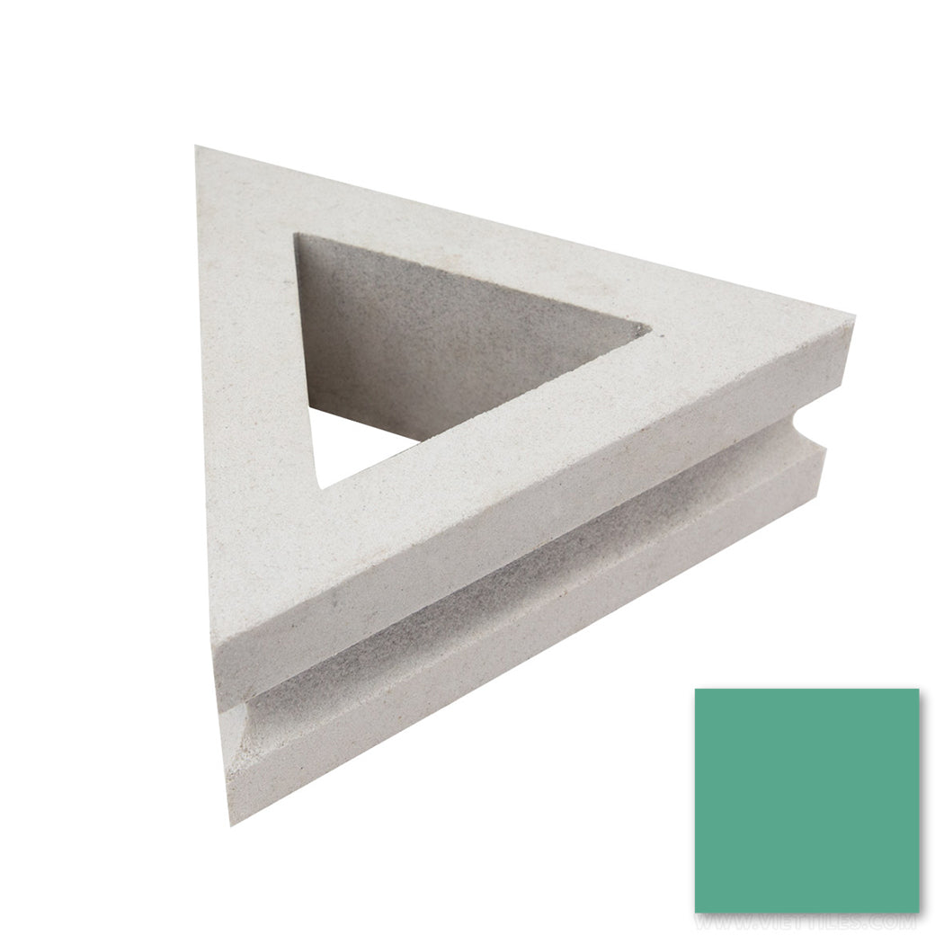 The Nui Triangular by New York Cement Tile, a mid-century modern concrete breeze block, rests above a green swatch.