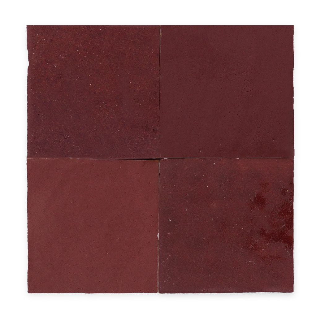 Four square, dark red tiles arranged in a grid with slight texture and variations in color.