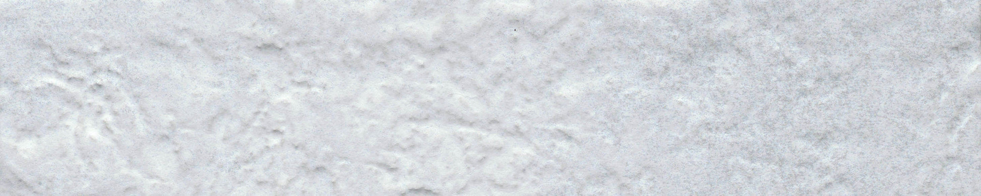 Close-up of New York Cement Tile's Silver - Brique - Sample, a textured white tile with soft shadows and creased details.