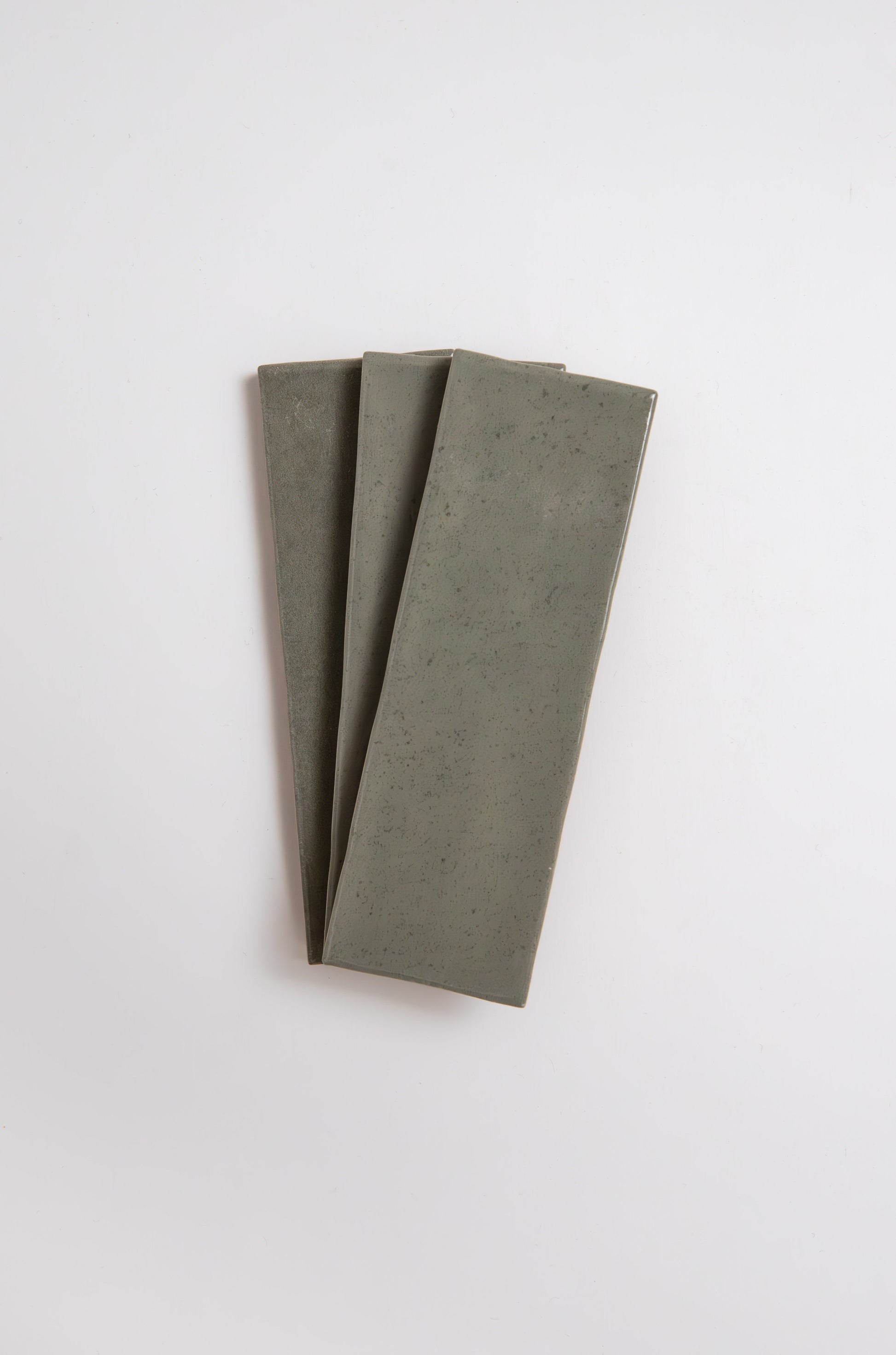 Three Skye Green ceramic tiles from Cottage Ivy arranged in a fan shape on a white background.