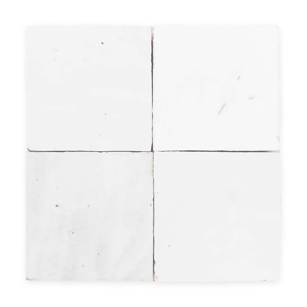 Four white square tiles with slight imperfections and visible grout lines forming a grid pattern.