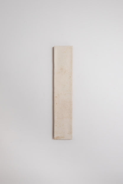 A tall, narrow Cottage Ivy Snowshill White tile sample is mounted vertically on a plain white wall.