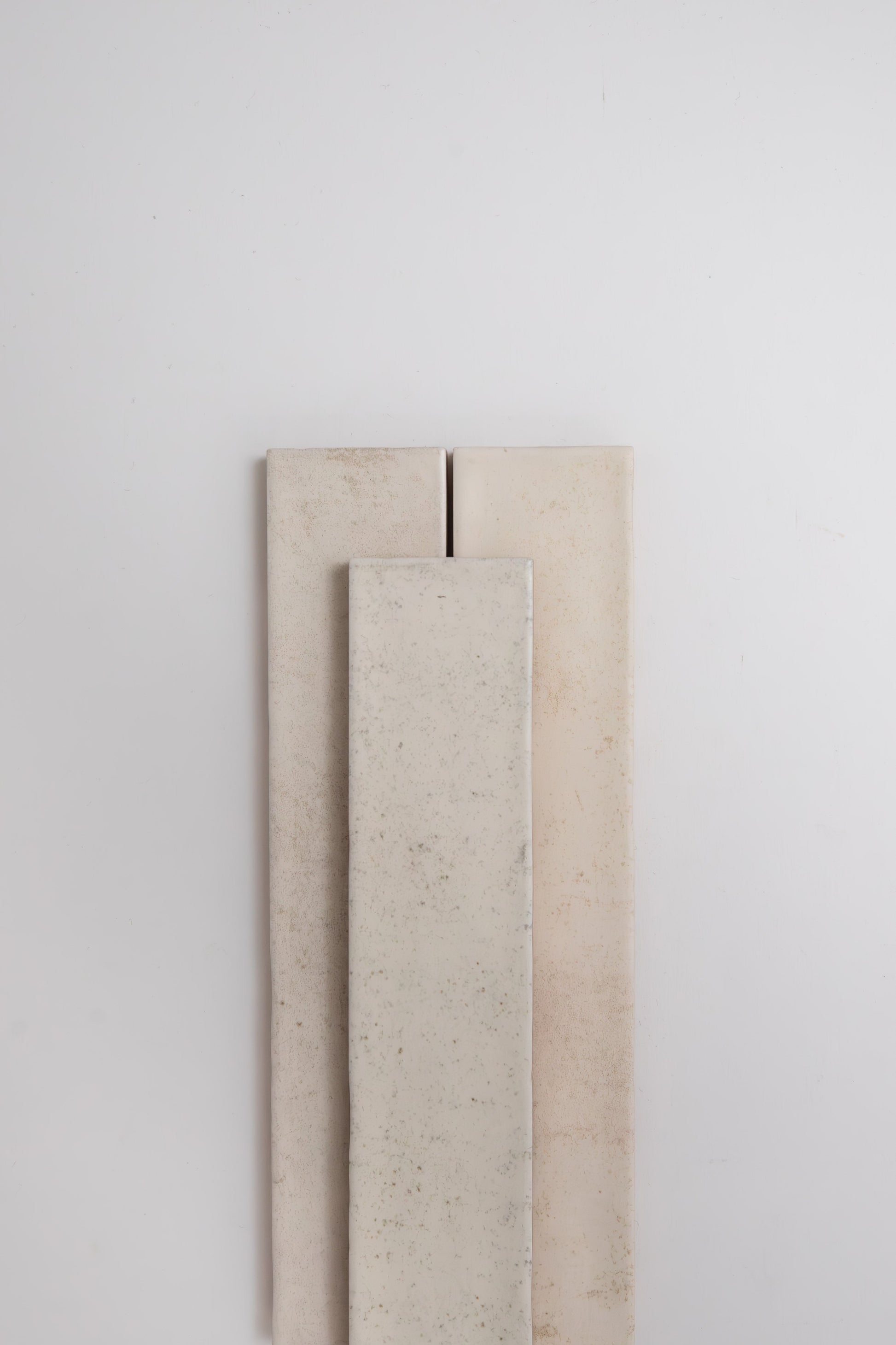 Three Snowshill White samples by Cottage Ivy are standing upright against a plain white wall.