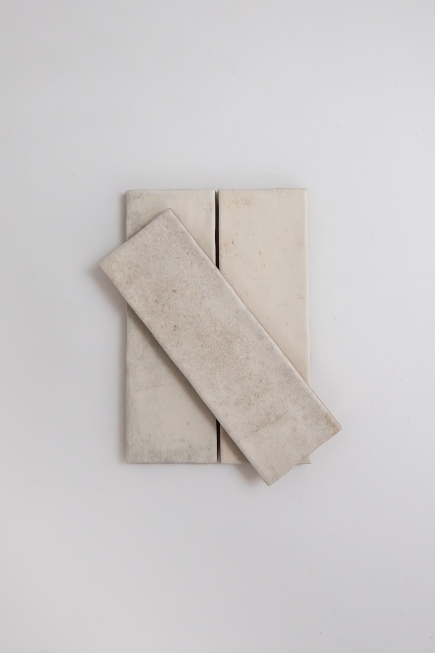 Three Snowshill White tile samples by Cottage Ivy, with one tile diagonally stacked over two vertical tiles.