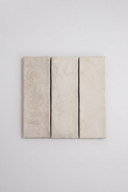 Three vertical Snowshill White Extra Sample tiles by Cottage Ivy, off-white with slight texture on a plain white wall.