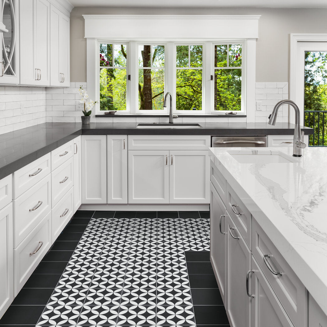 Modern kitchen with white cabinets, New York Cement Tile 2200-Solid Black 4x4 counters, and large windows to greenery.