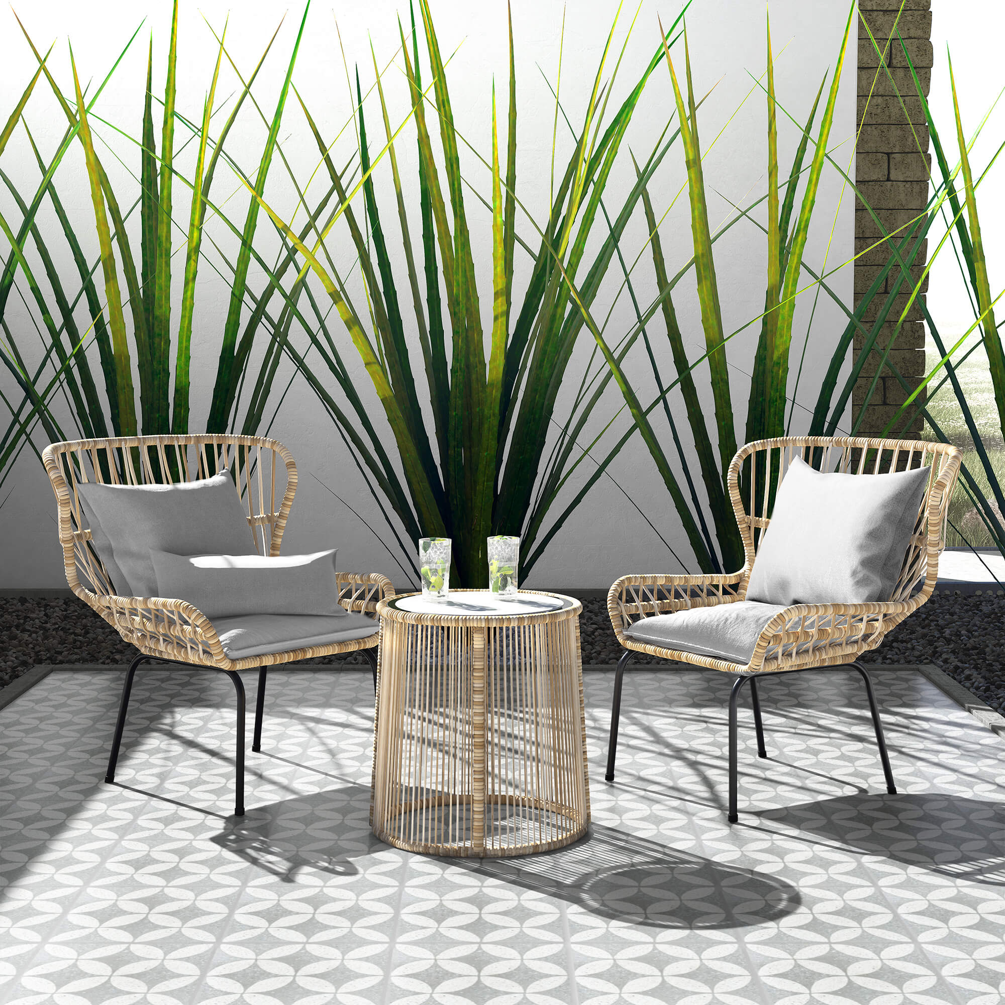 Two wicker chairs and a round table are on NT20-061 2219 flooring by New York Cement Tile, surrounded by tall plants.