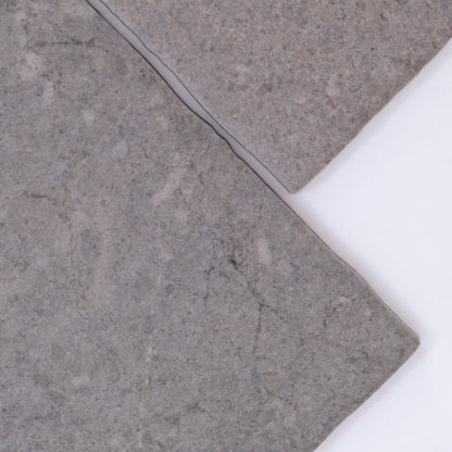 Close-up of two Toba Basilica R11 tile samples with uneven edges, overlapping on a white background.
