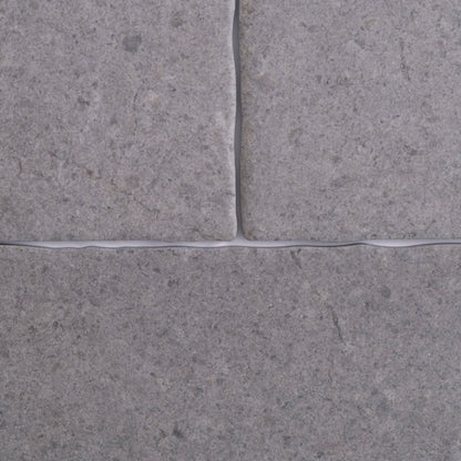 Close-up of four Toba Basilica R11 tiles by Toba, gray with visible grout lines in a cross pattern.