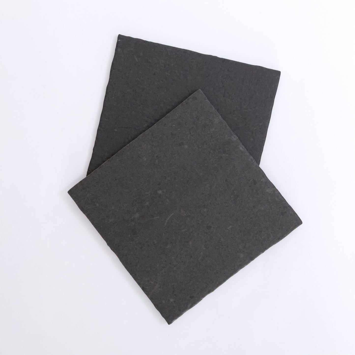 Two square, flat Toba Black R11 slate tiles by Toba overlapping on a plain white background.