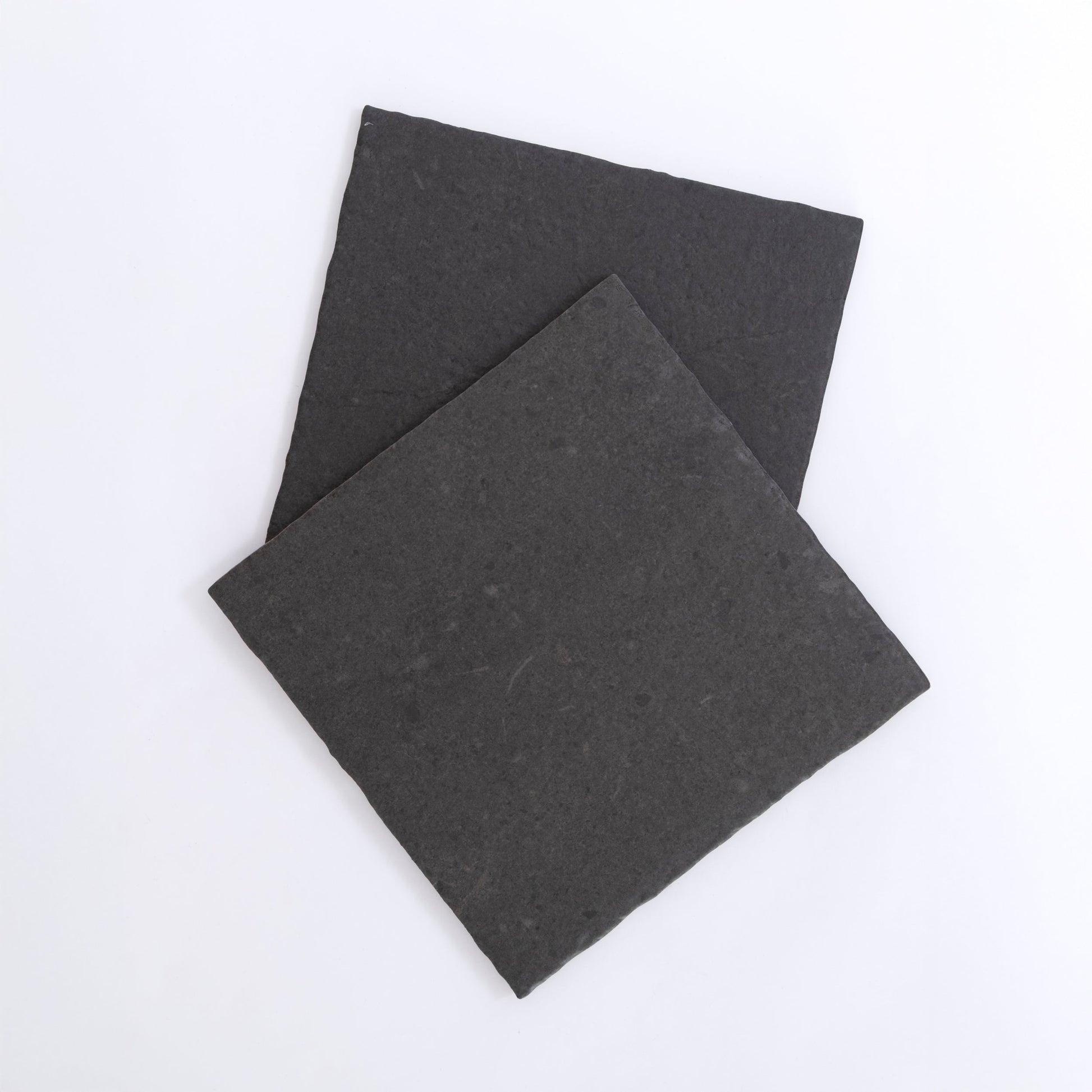 Two square, flat Toba Black R11 slate tiles by Toba overlapping on a plain white background.