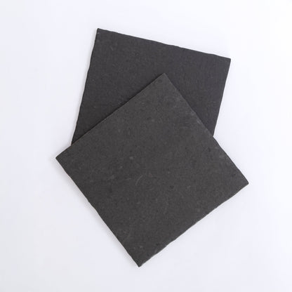 Two square, flat Toba Black R11 slate tiles by Toba overlapping on a plain white background.