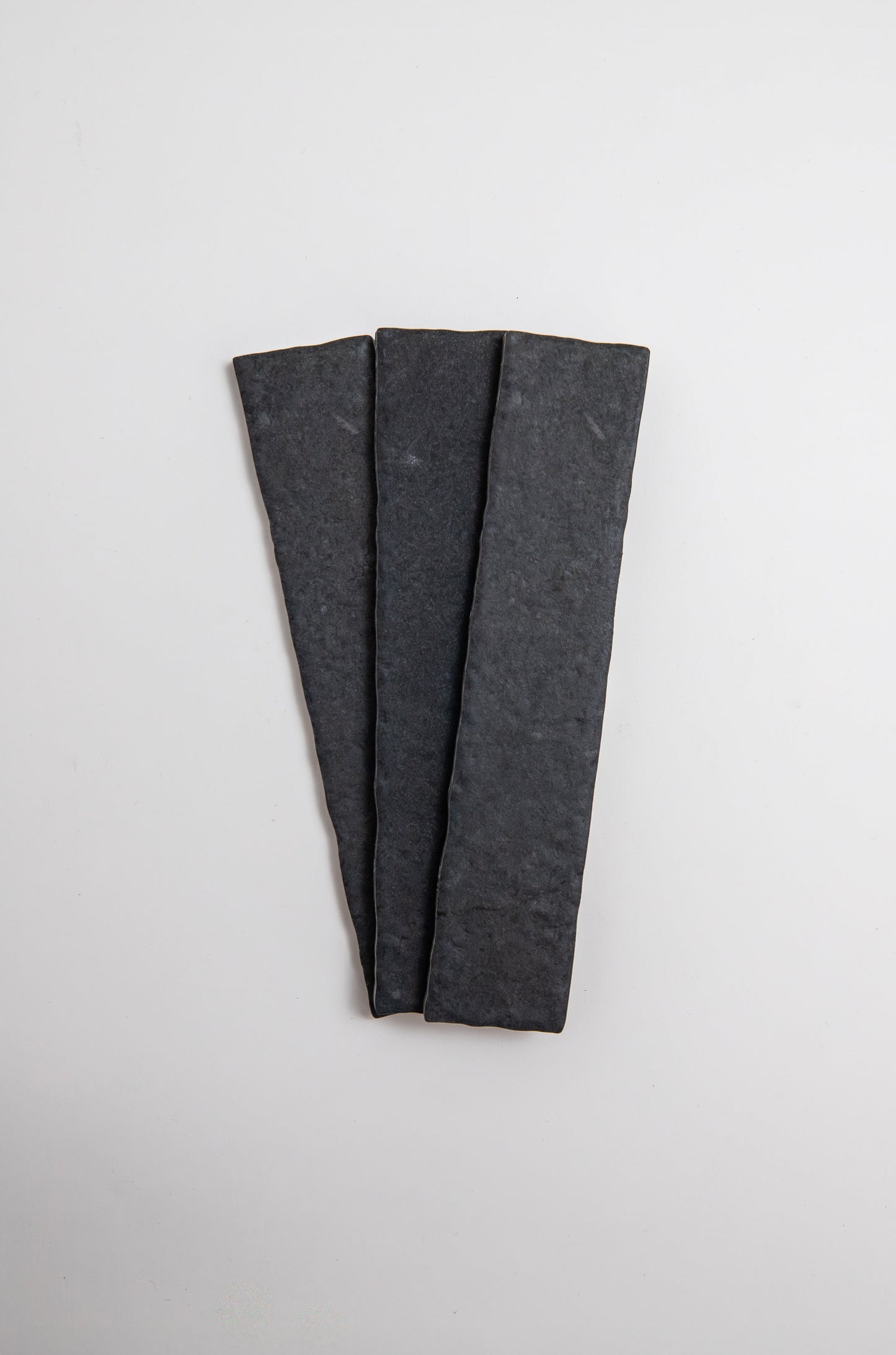 Three Toba Black R11 sample tiles by Toba arranged in a fan shape on a plain white background.