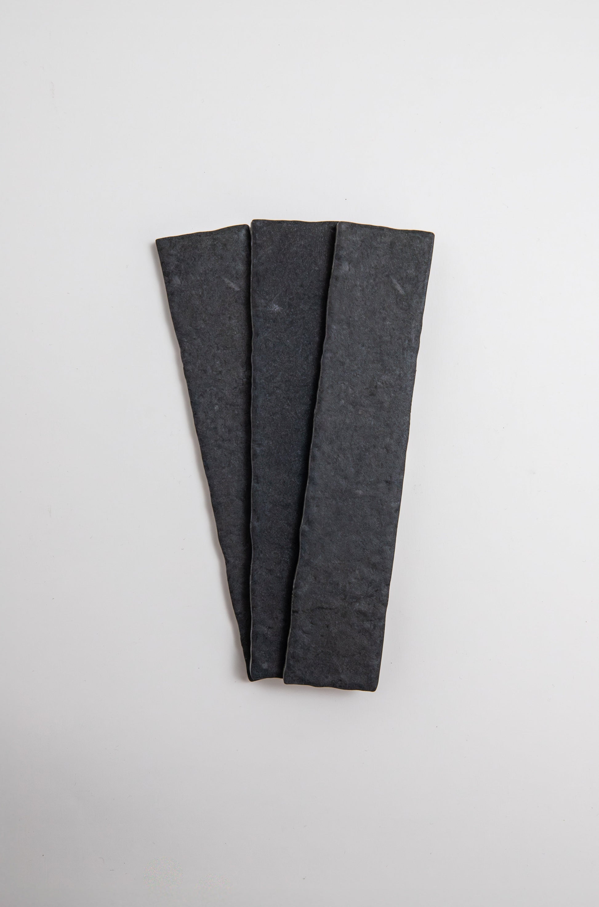 Three Toba Black R11 sample tiles by Toba arranged in a fan shape on a plain white background.