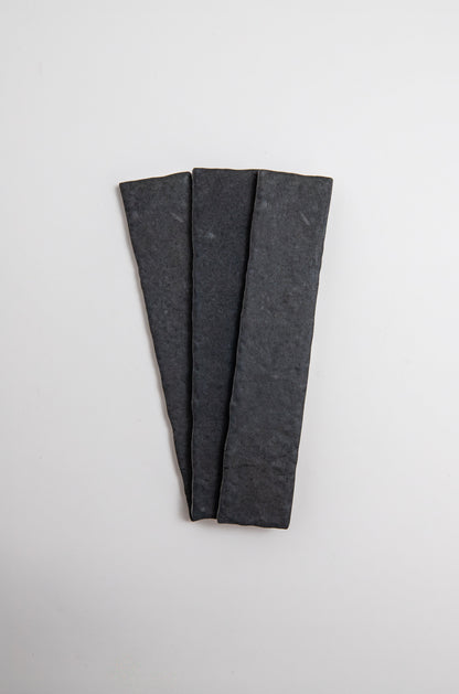 Three Toba Black R11 sample tiles by Toba arranged in a fan shape on a plain white background.