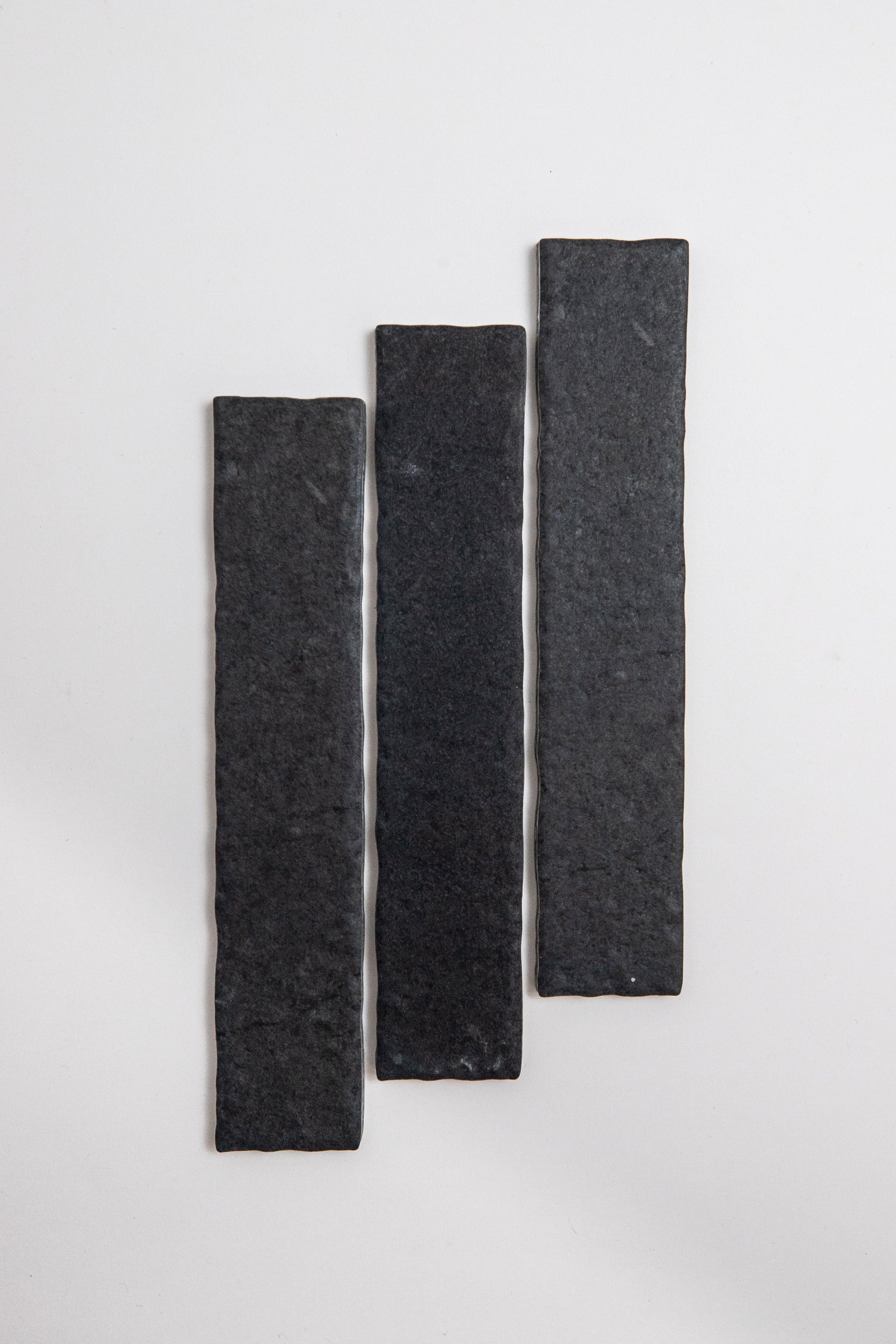 Three Toba Black R11 sample tiles from Toba, rectangular and textured, arranged vertically on a white background.