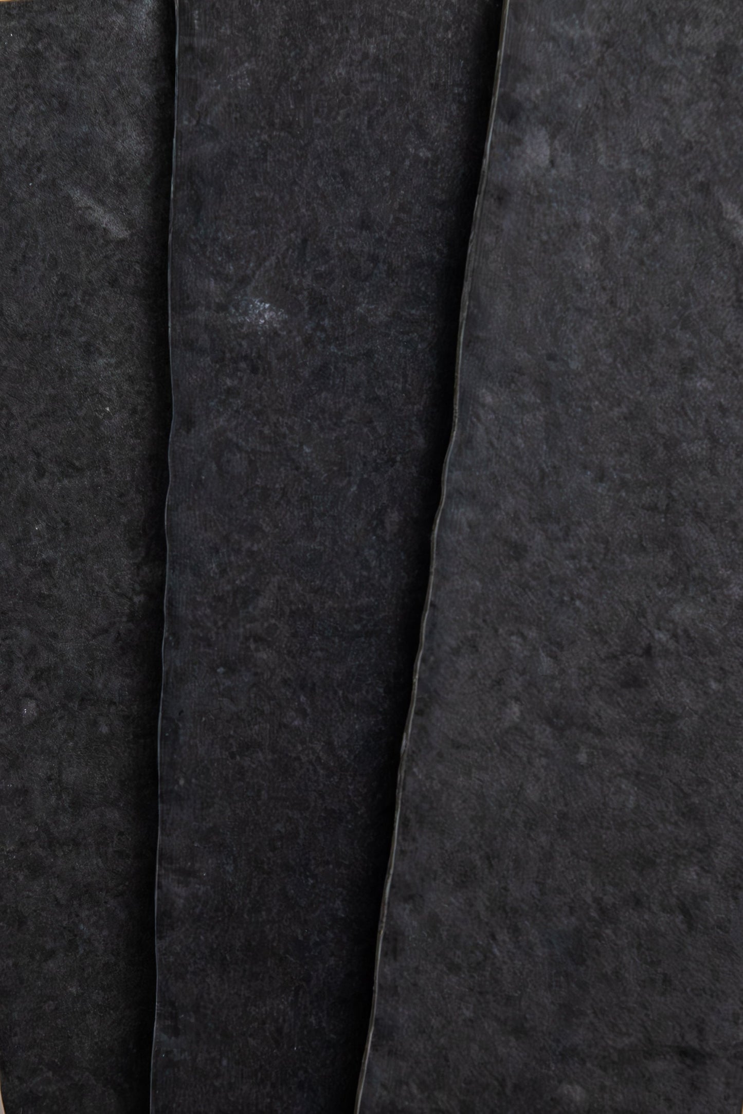 Close-up of three overlapping Toba Black R11 sheets by Toba, showing rough textures and uneven edges.