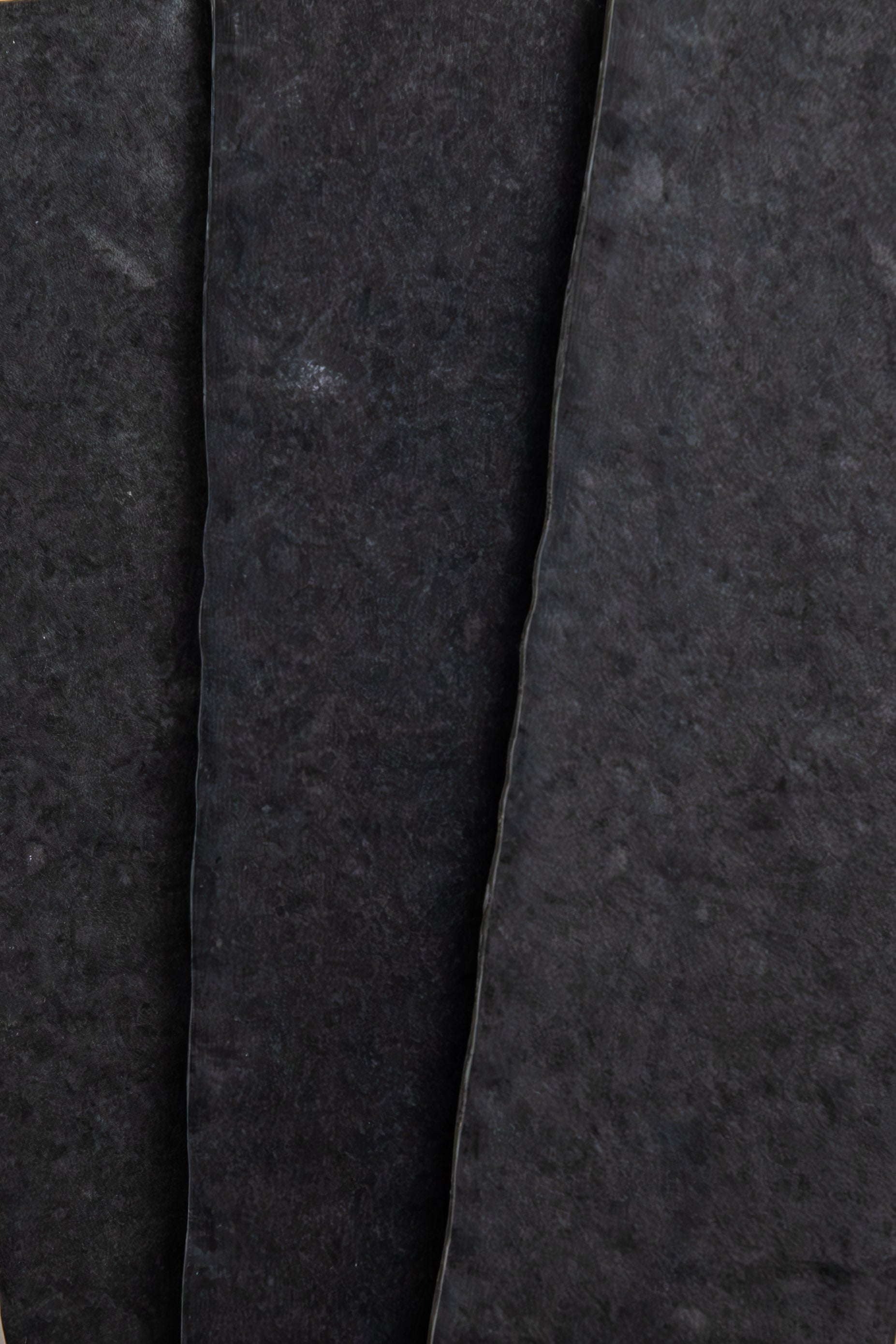 Close-up of three overlapping Toba Black R11 sheets by Toba, showing rough textures and uneven edges.