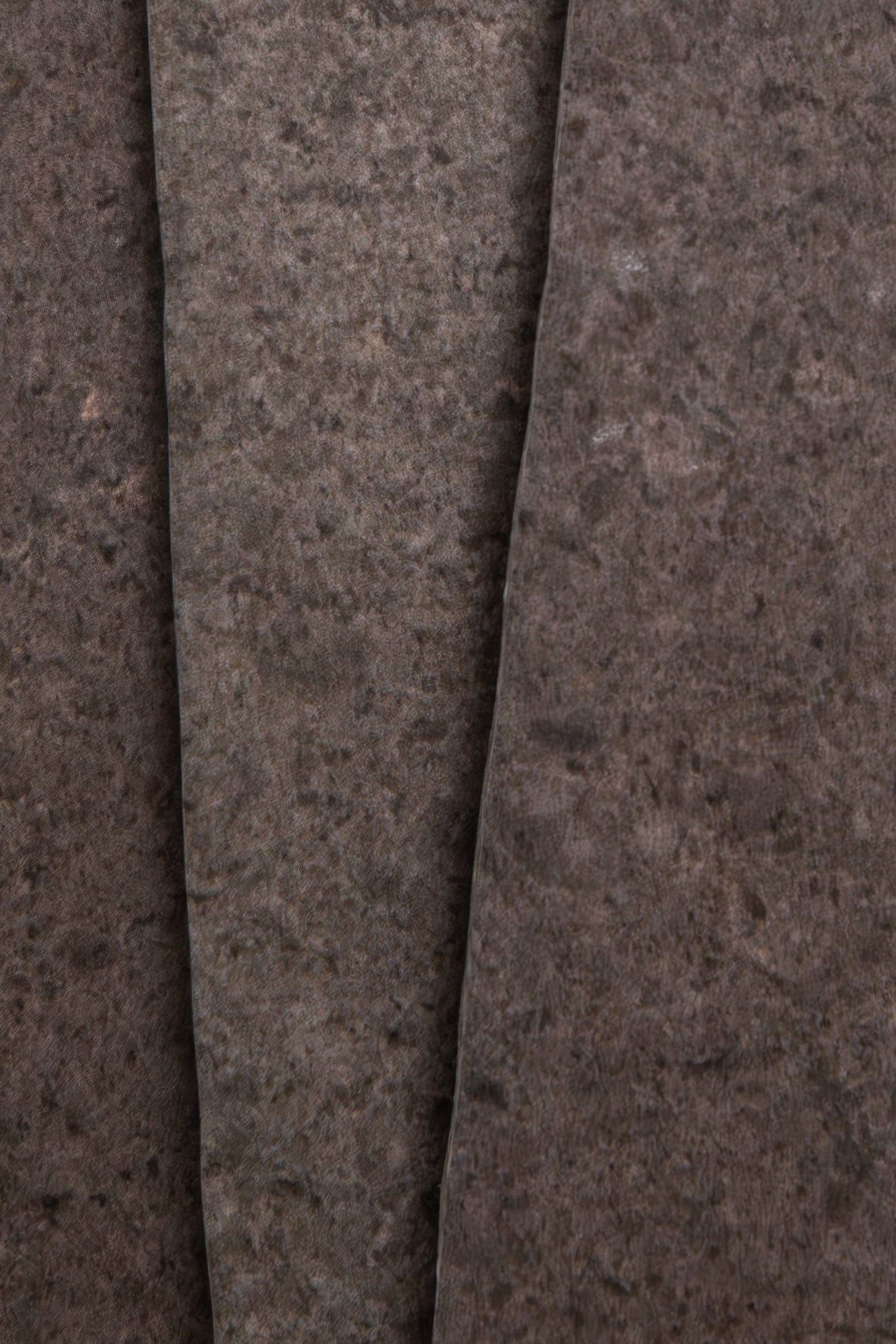 Close-up of three overlapping Toba Brun R11, Sample sheets by Toba, featuring a dark, stone-like textured surface.