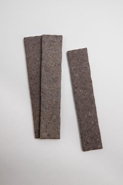 Three Toba Brun R11 sample tiles by Toba arranged on a white surface, two overlapping left, one separate on the right.