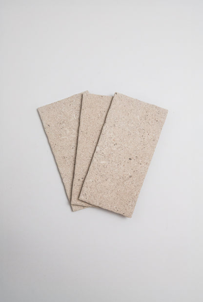 Three Toba Taupe R11 sample tiles by Toba displayed in a fan shape on a plain light background.