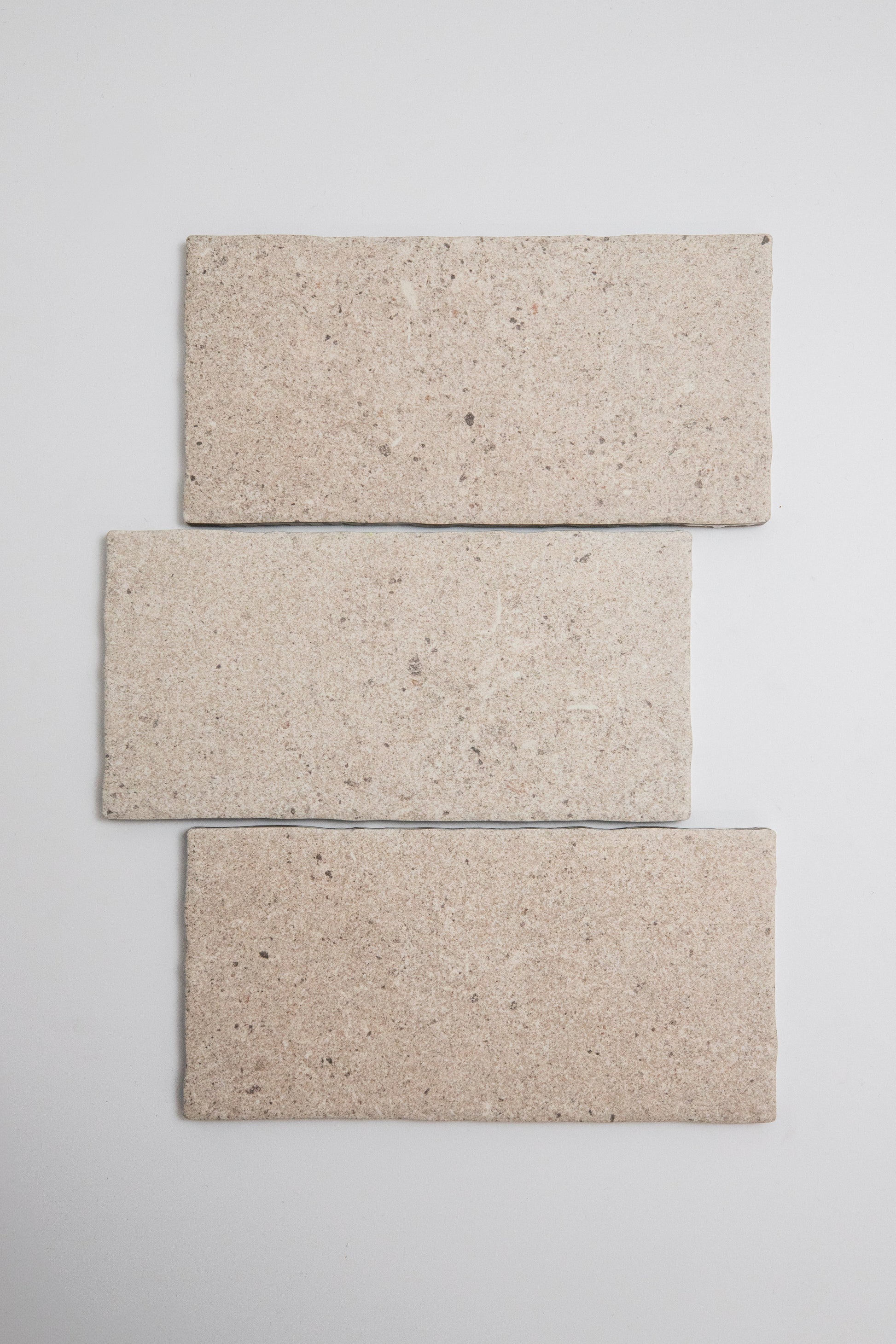 Three Toba Taupe R11, Sample tiles by Toba are arranged vertically in a staggered stack on a light gray background.