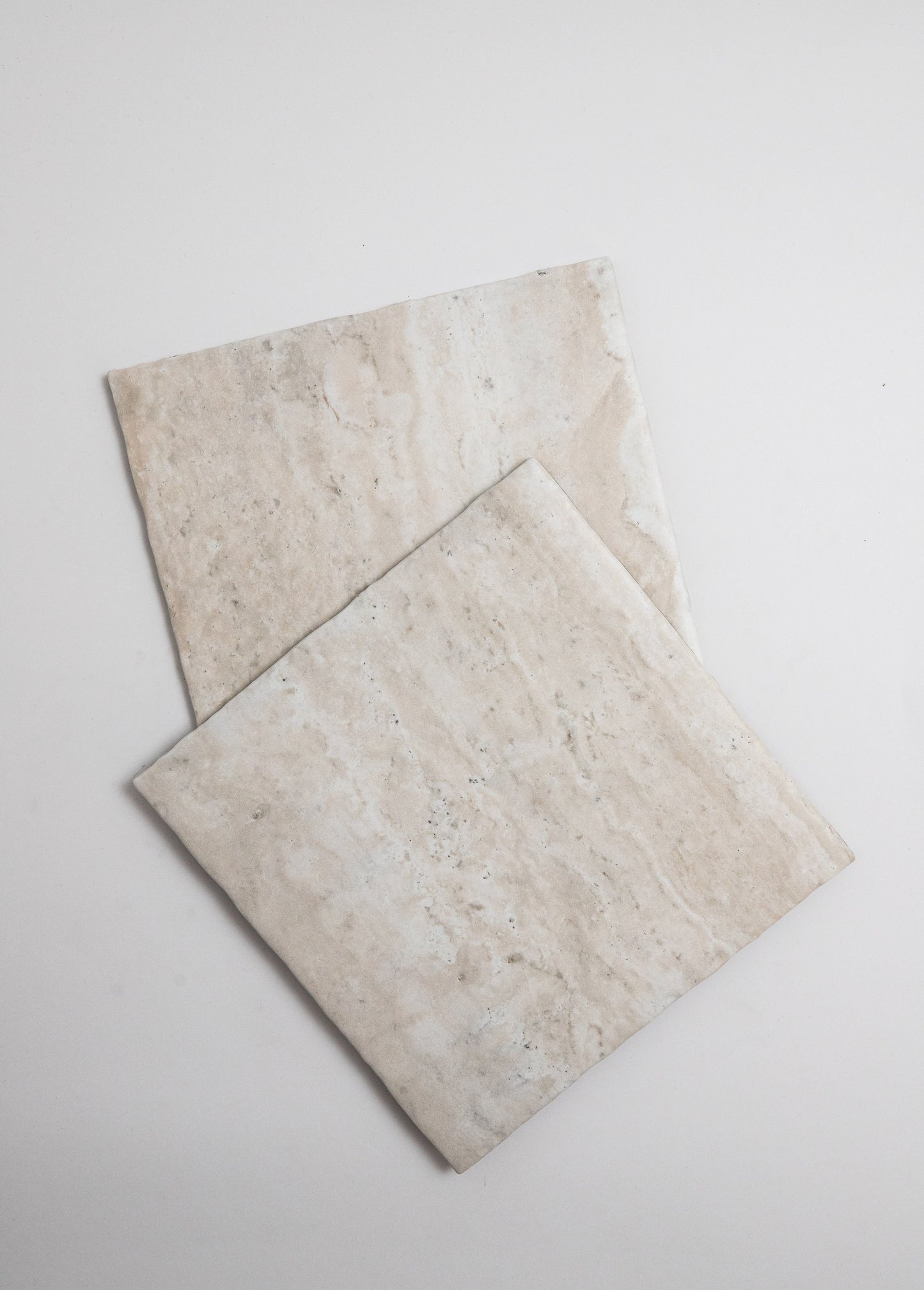 Two Tosca Travertine tiles with subtle veins overlap on a plain white background.
