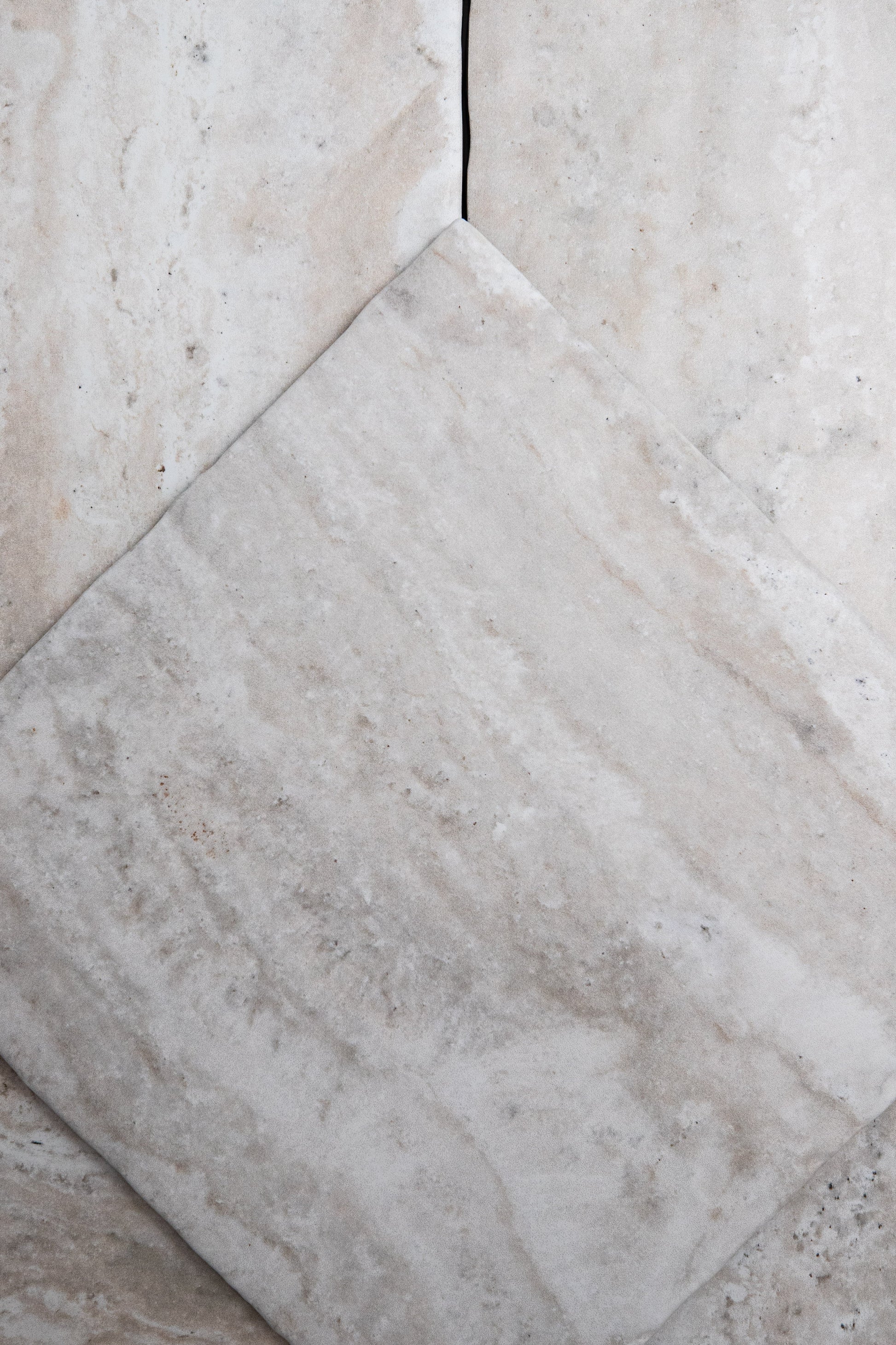 A close-up of Tosca Travertine tiles, one set diagonally, showing natural veining and subtle color variations.