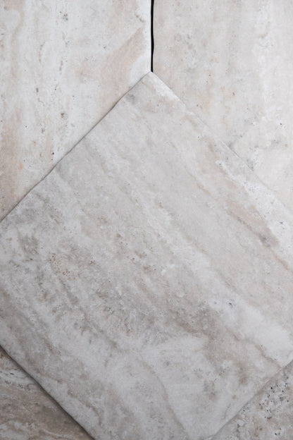 A close-up of Tosca Travertine tiles, one set diagonally, showing natural veining and subtle color variations.