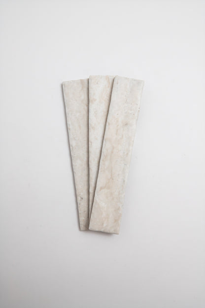 Three Tosca Travertine tiles in a fan shape are displayed on a plain white background.