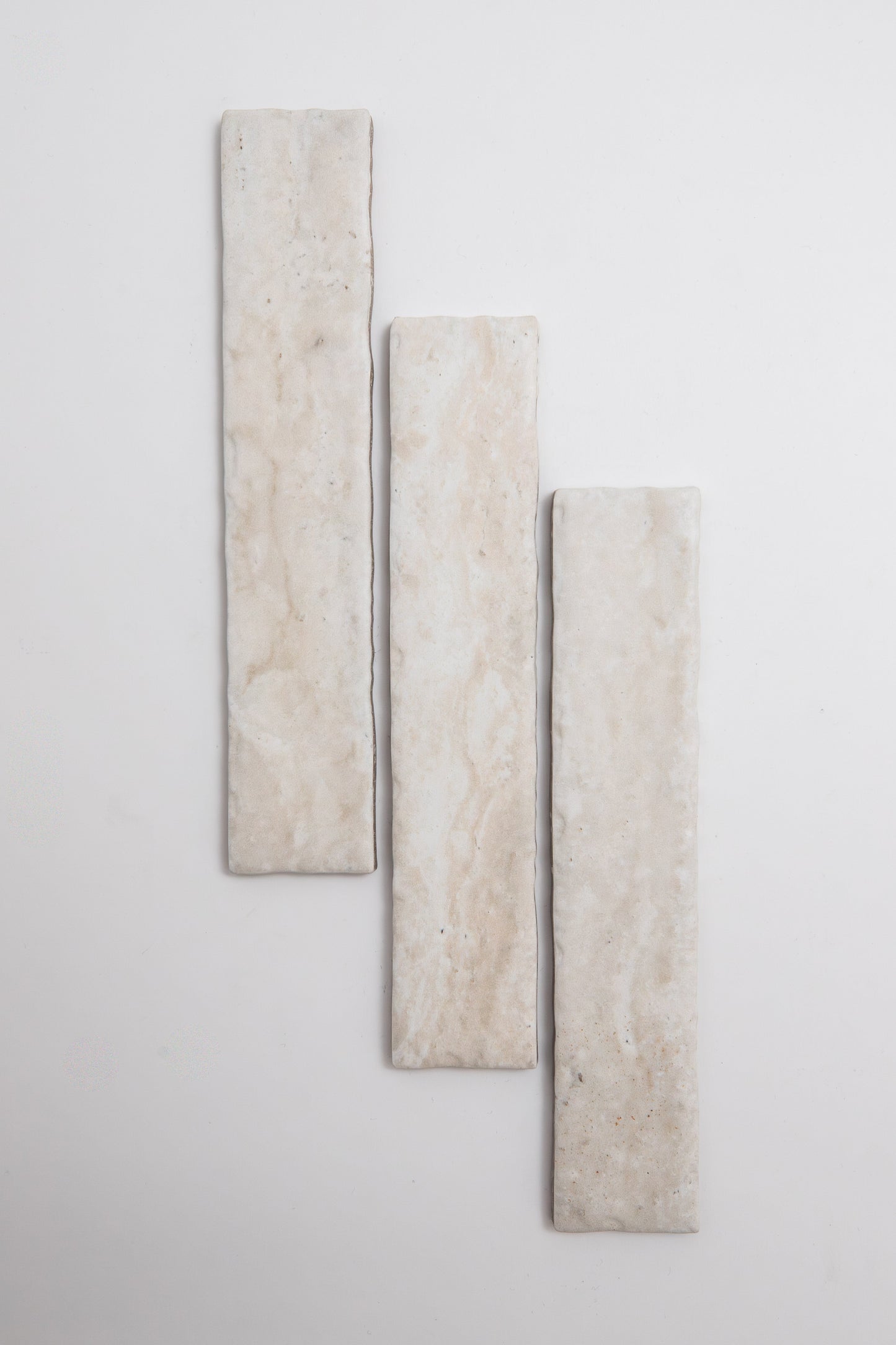 Three Tosca Travertine rectangular beige tiles arranged vertically on a white background, slightly staggered in height.