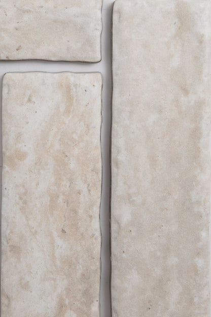 Four Tosca Travertine tiles, cream-colored with textured, uneven surfaces, are placed closely together.