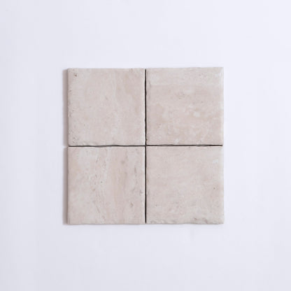 Four Tosca Travertine tiles in light beige are arranged in a grid on a white background.