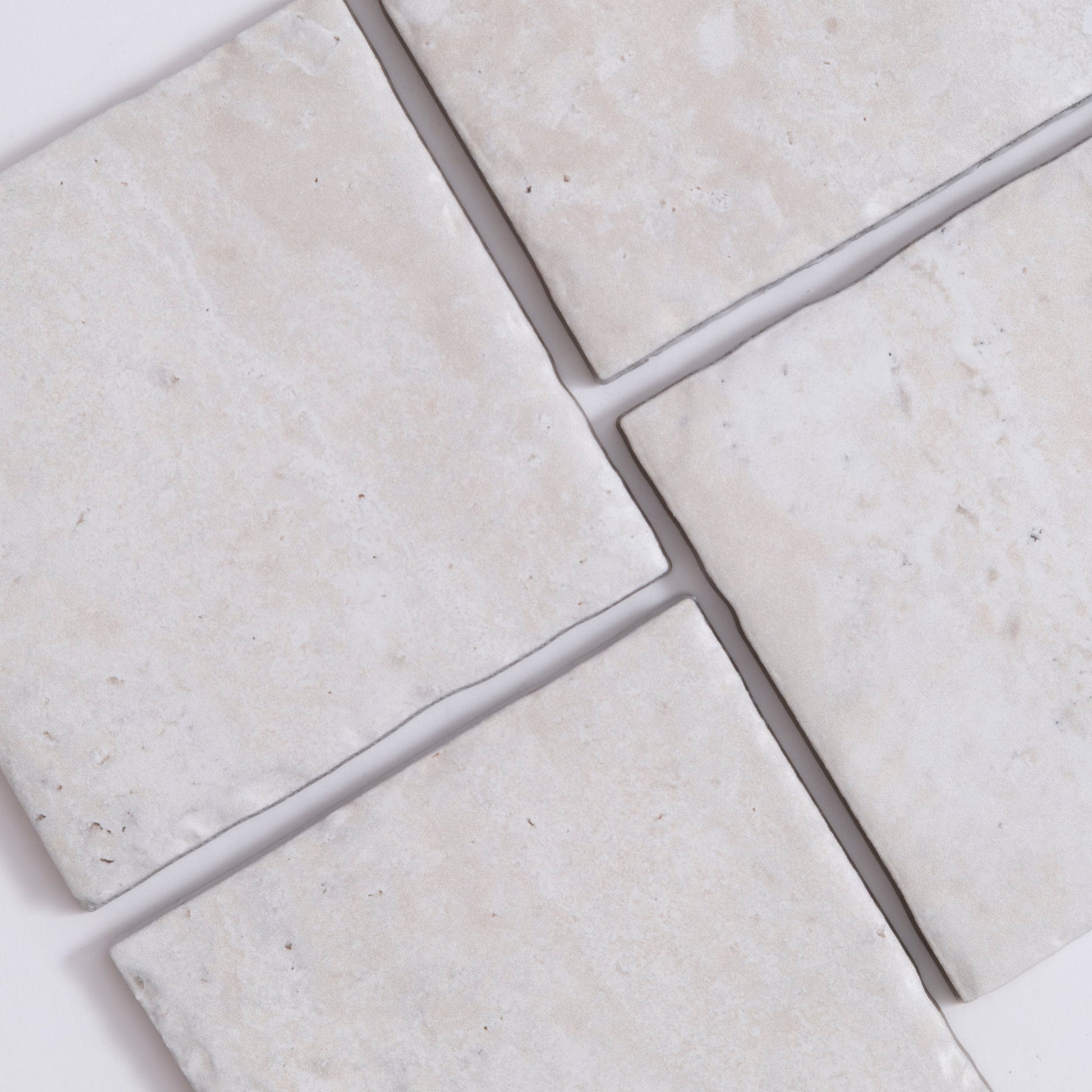 Four Tosca Travertine ceramic tiles with a matte, lightly textured surface are arranged on a white background.