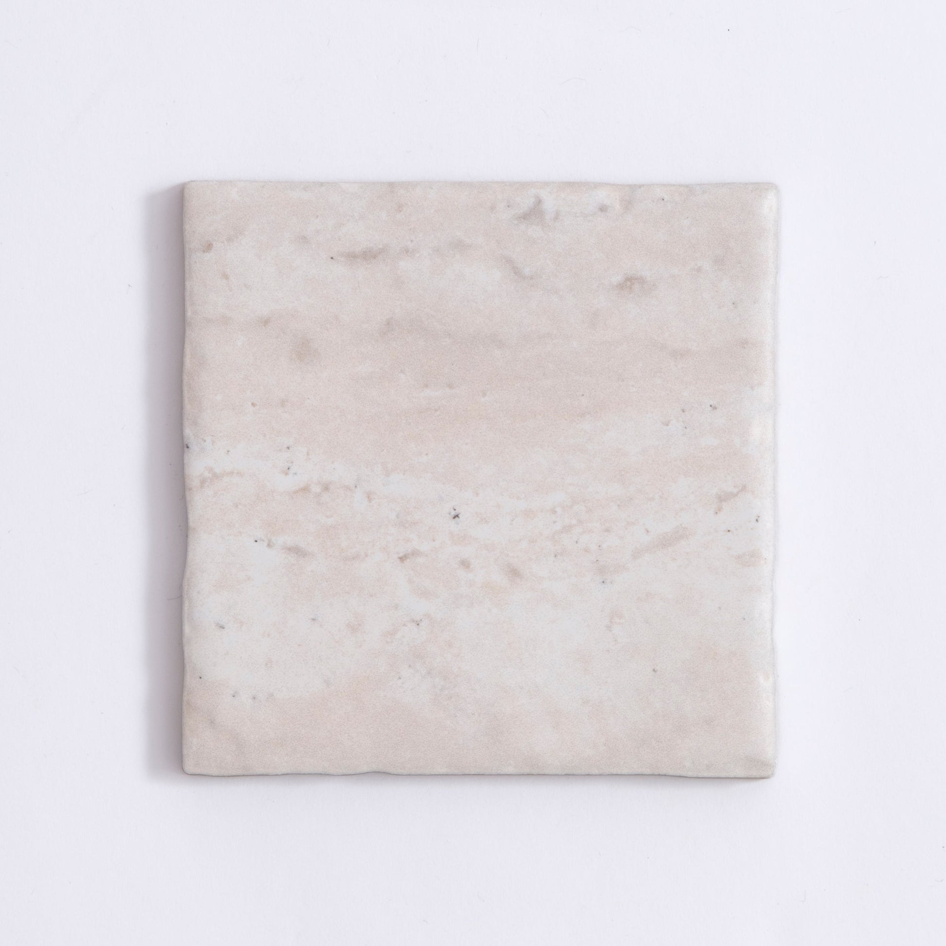 The Tosca Travertine is a square, light beige ceramic tile with a subtle marbled texture and slightly uneven surface.