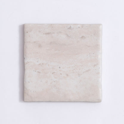 The Tosca Travertine is a square, light beige ceramic tile with a subtle marbled texture and slightly uneven surface.