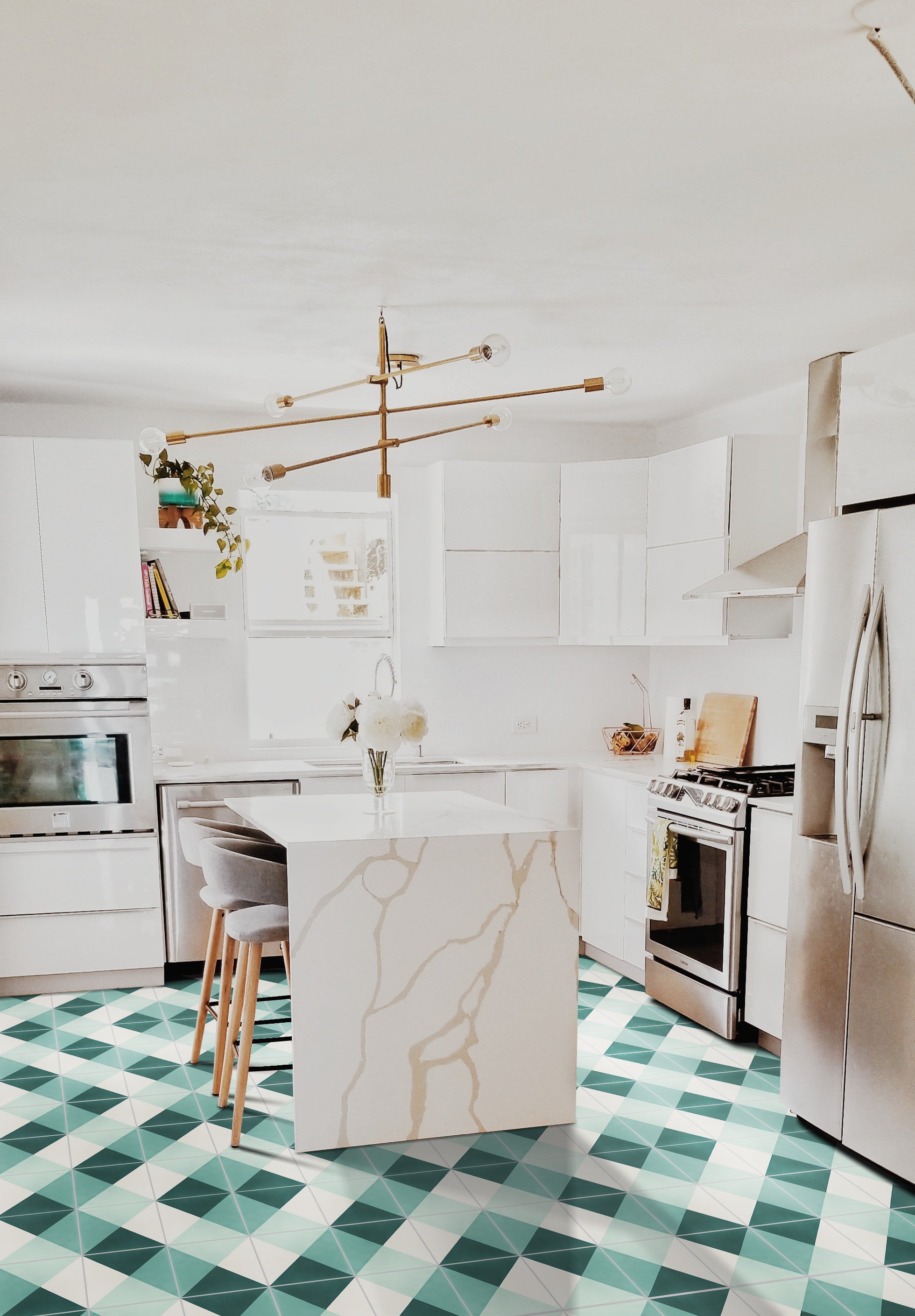 Modern white kitchen with geometric green tile floor, marble island, stainless steel appliances, and gold chandelier.