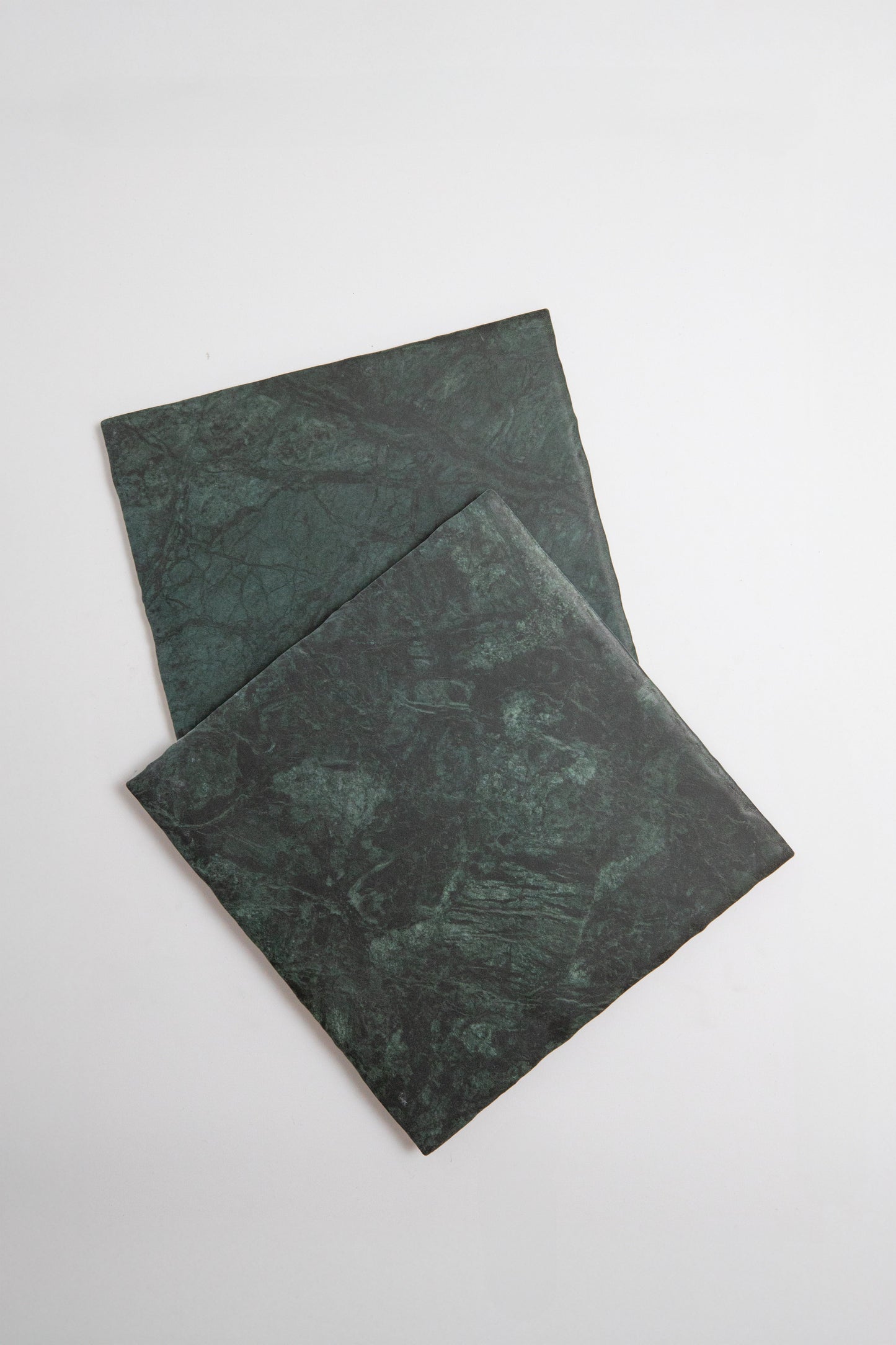 Two Tosca Verde Tia marble samples in dark green, overlapping on a white background.