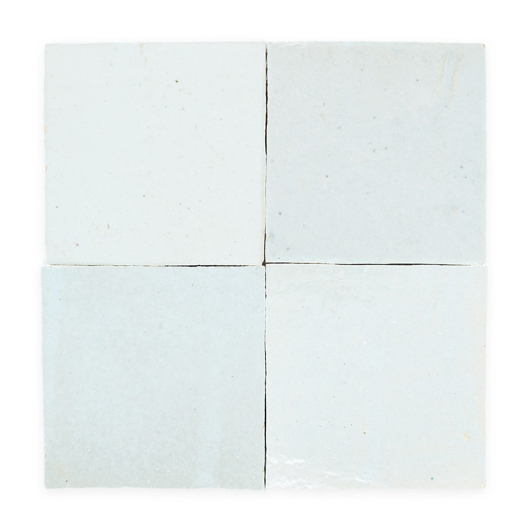 Four glossy, off-white ceramic tiles arranged in a square with visible seams and slight texture variations.
