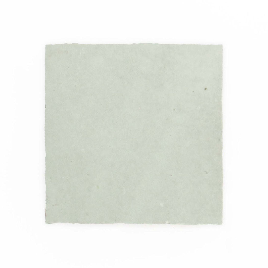 A Mint Frost 2X2 sample by New York Cement Tile: a plain, light gray square sheet with rough edges on white background.