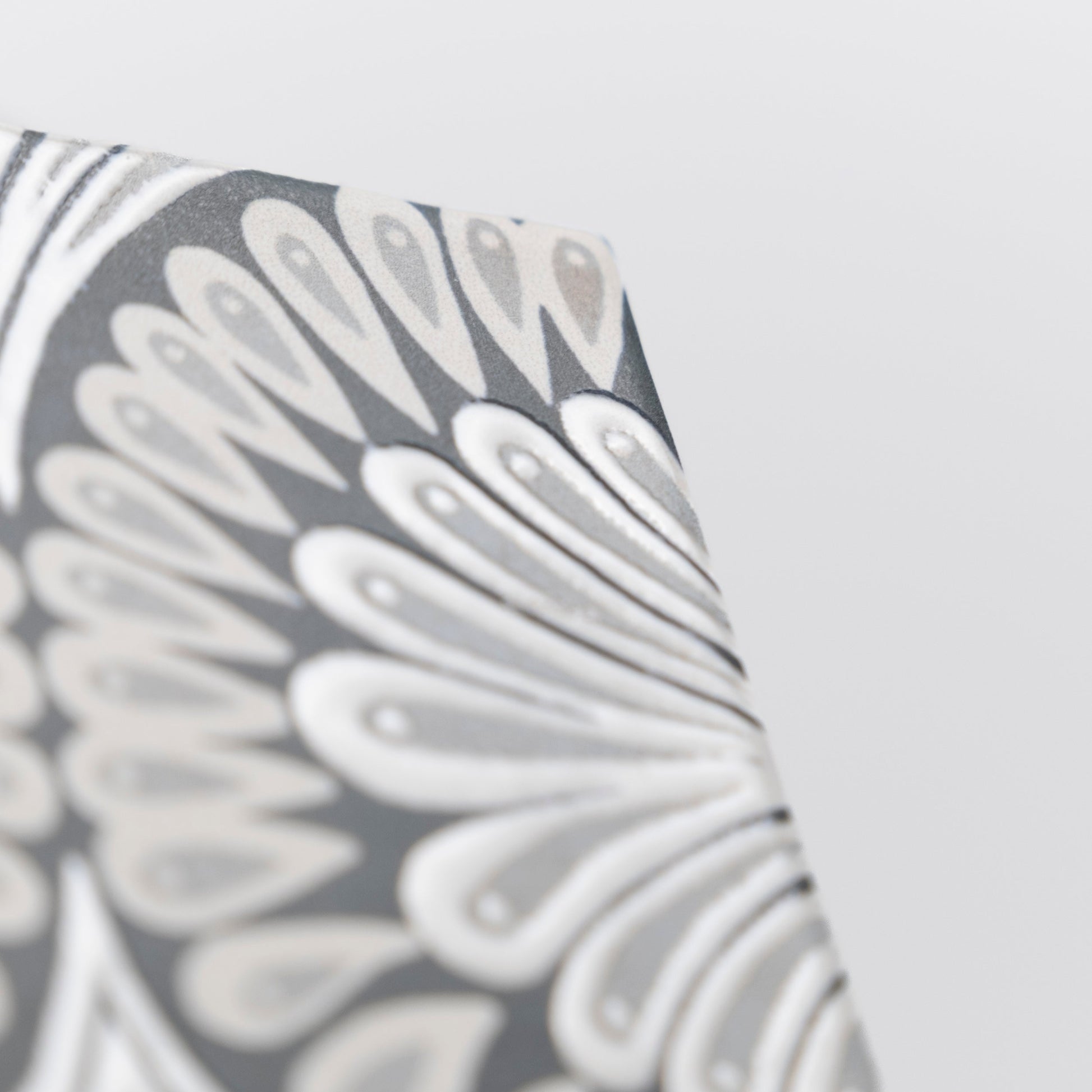 Close-up of Cottage Ivy Zoe Deco sample featuring a gray and white abstract floral pattern on a textured surface.